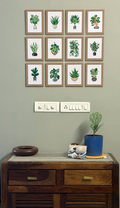 Tweleve framed dimaond painting pictures on a wall above a wooden cabinet with decorative items.